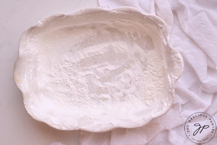 An oiled and well starched, white casserole dish sitting on a white surface.