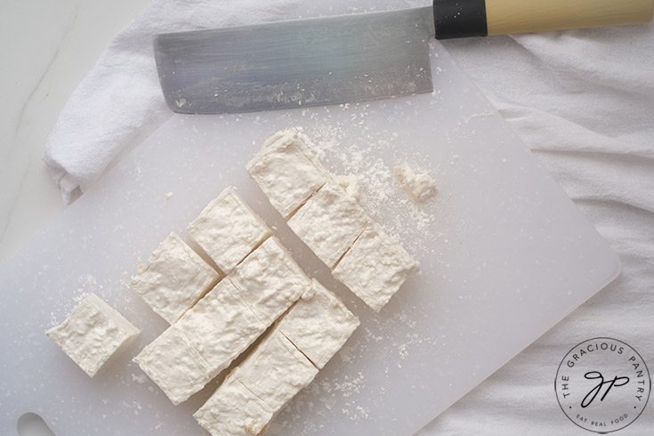 The finished marshmallows, cut on a white cutting board.