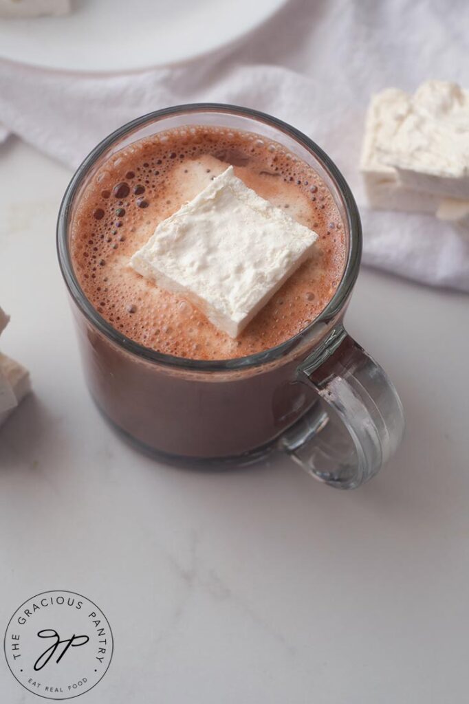 A single, square marshmallow floating in a mug of hot chocolate.