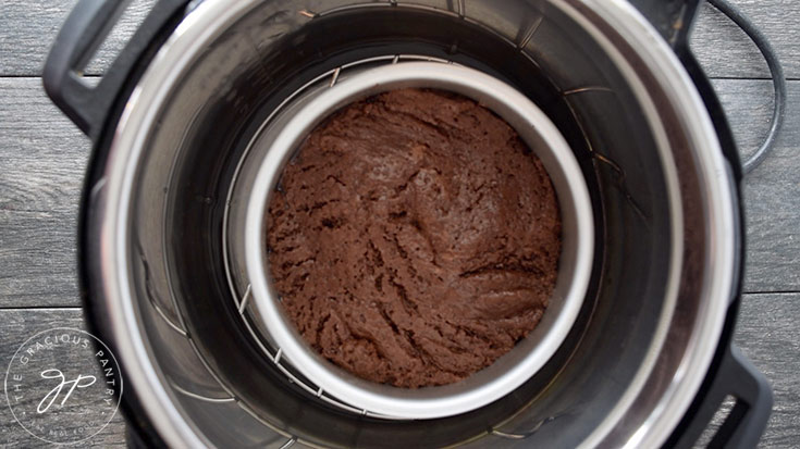 A small cake pan with cake batter in it rests on a trivet inside an Instant Pot.