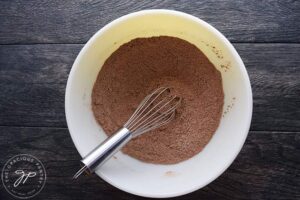 A dry flour mixture in a white mixing bowl. A whisk sits in the bowl.