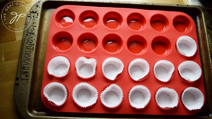 Paper liners lining a red, mini muffin pan.