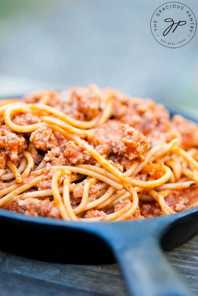 A cast iron skillet filled with this Skillet Spaghetti Recipe, sitting on a wooden table.