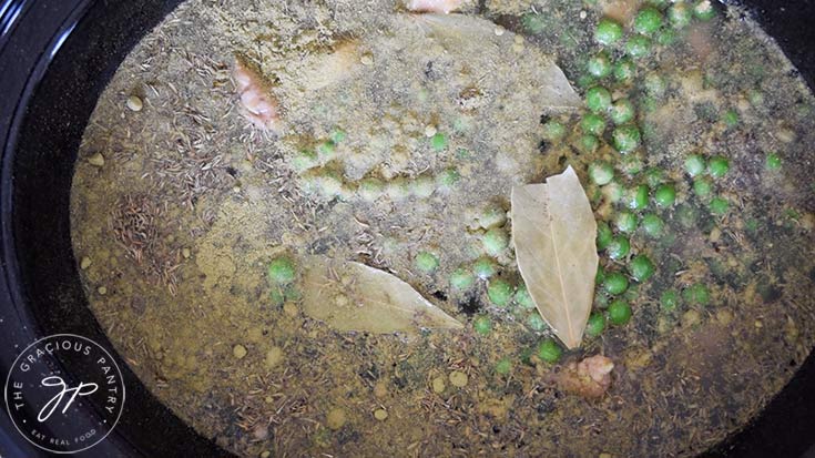 Spices, broth and peas in a slow cooker.