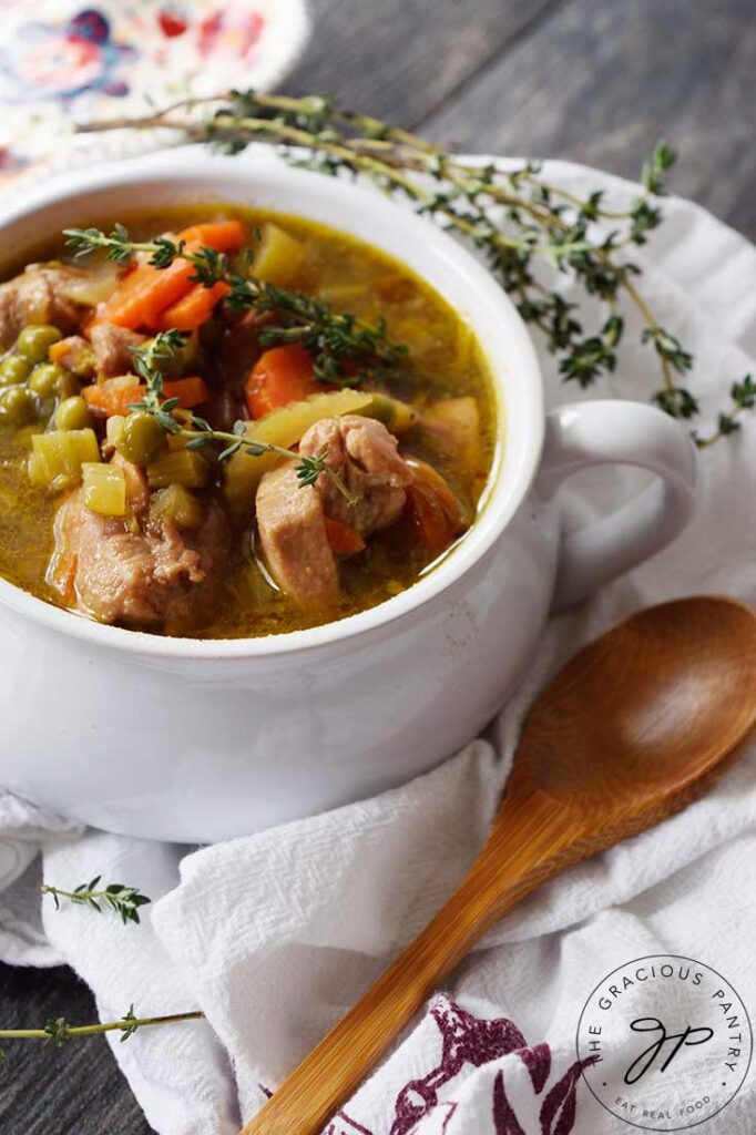 A side view of a white bowl filled with chicken stew.