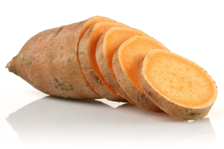 A partially sliced sweet potato on a white background.
