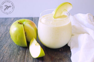 The finished Tart Green Apple Smoothie Recipe poured in a glass and garnished with a green apple slice.
