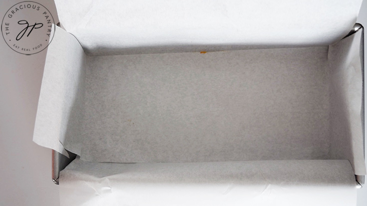 A standard loaf pan lined with cut parchment paper.
