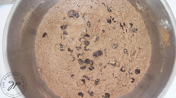 A dry flour mixture with chocolate chips in a stainless steel mixing bowl.