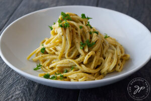 The finished, dairy-free carbonara served in a white pasta bowl and garnished with fresh parsley.