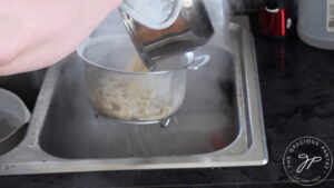 Straining water from pasta over a kitchen sink.