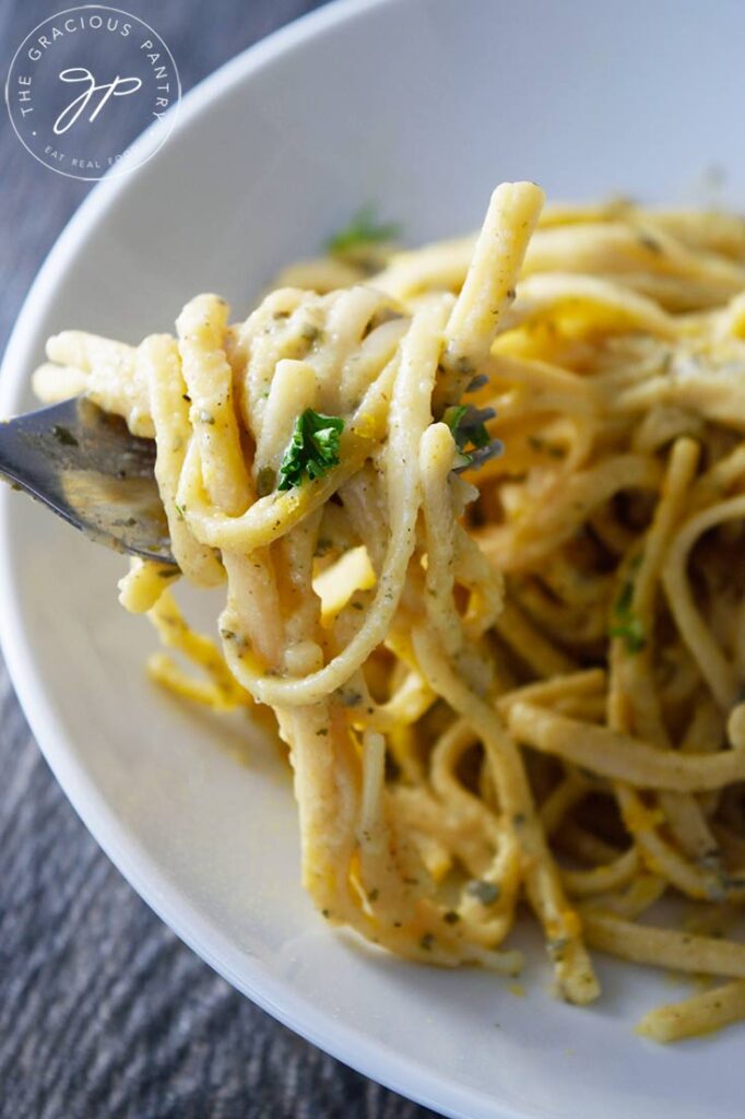 A fork with Dairy-Free Carbonara on it lifted up out of a bowl.