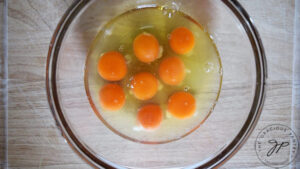 Egg yolks and whites in a clear, glass, mixing bowl