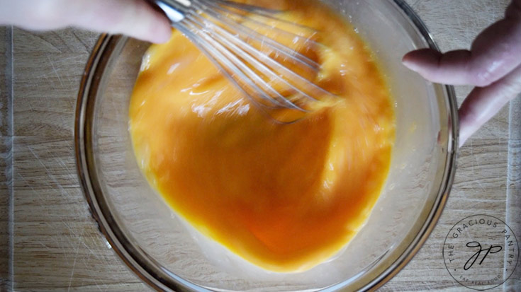 Whisking eggs and water together in a mixing bowl.