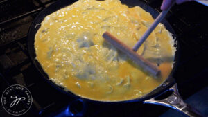 Spreading the egg batter over a crepe pan with a crepe spreader.
