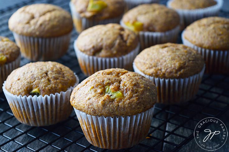 Kiwi muffins sitting on a black, wire cooling rack.