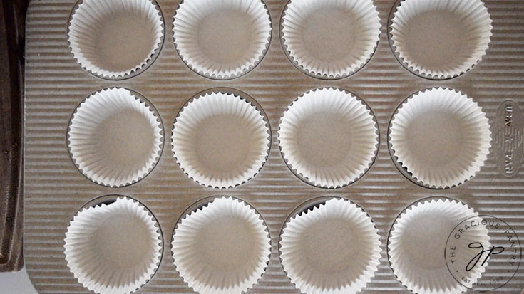 A muffin pan lined with white, paper liners.