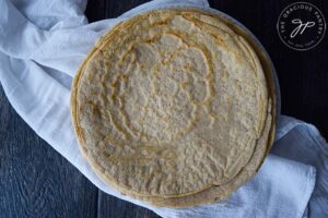 An overhead view looking down onto a white plate with layers of crepes on it.