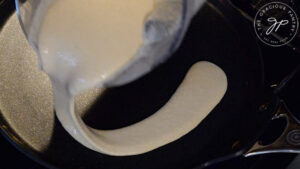 Pouring crepe batter onto a crepe pan.