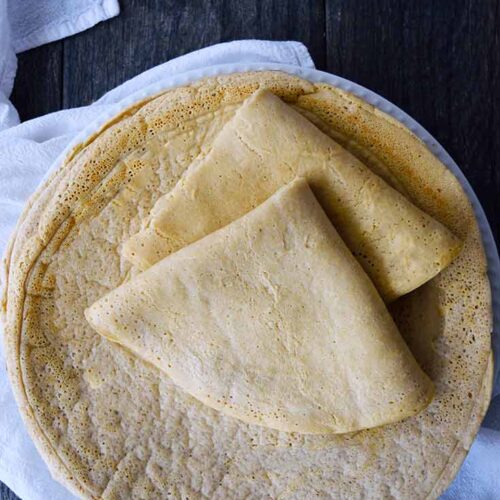 A stack of Oat Flour Crepes on a white plate. The top two crepes have been folded.