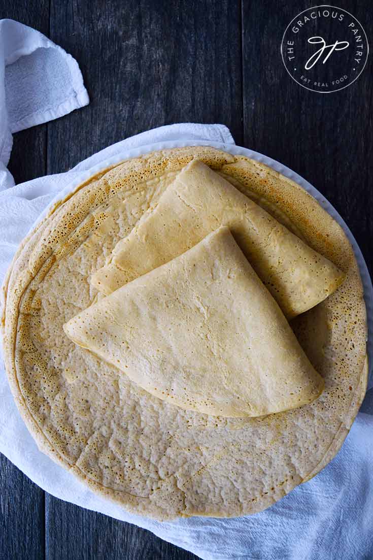 A stack of Oat Flour Crepes on a white plate. The top two crepes have been folded.