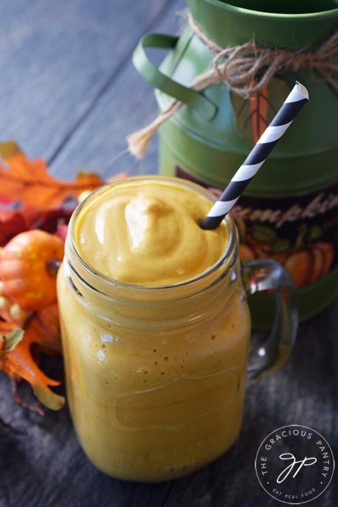 A Pumpkin Pie Smoothie in glass mug with a black and white stripped straw in it.