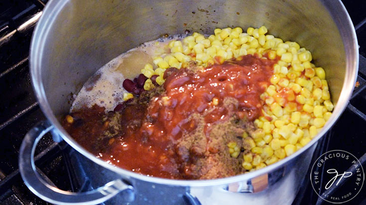 Corn, beans, spices and salsa added to ground turkey in a large stock pot.