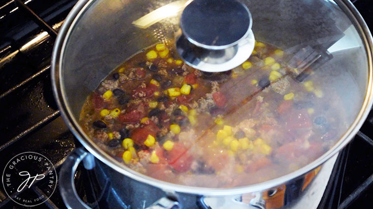 A lid placed on a stockpot filled with 2 Bean Turkey Chili.