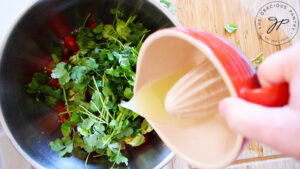 Lime juice being poured into a mixing bowl filled with Avocado Quinoa Salad Recipe ingredients.