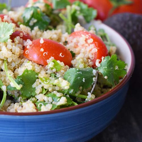 An up close view of a blue bowl filled with this Avocado Quinoa Salad.