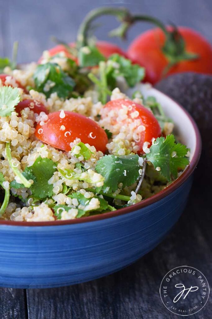 An up close view of a blue bowl filled with this Avocado Quinoa Salad.