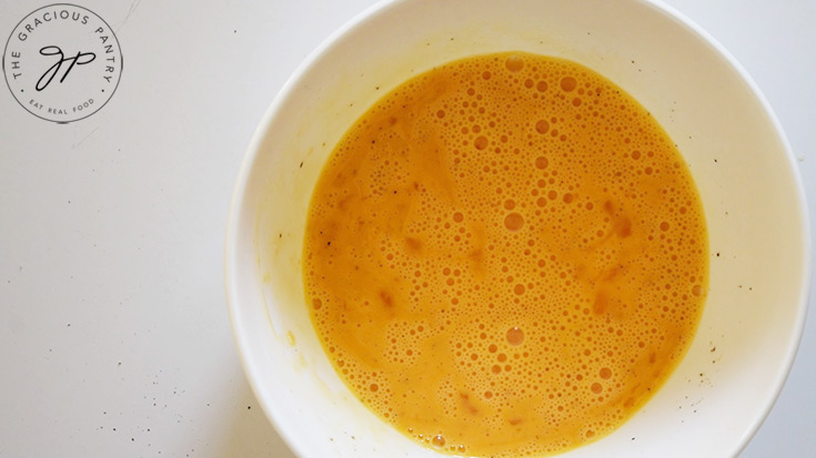 An egg mixture in a white mixing bowl.