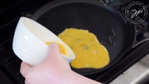 Pouring beaten egg mixture into a hot skillet.
