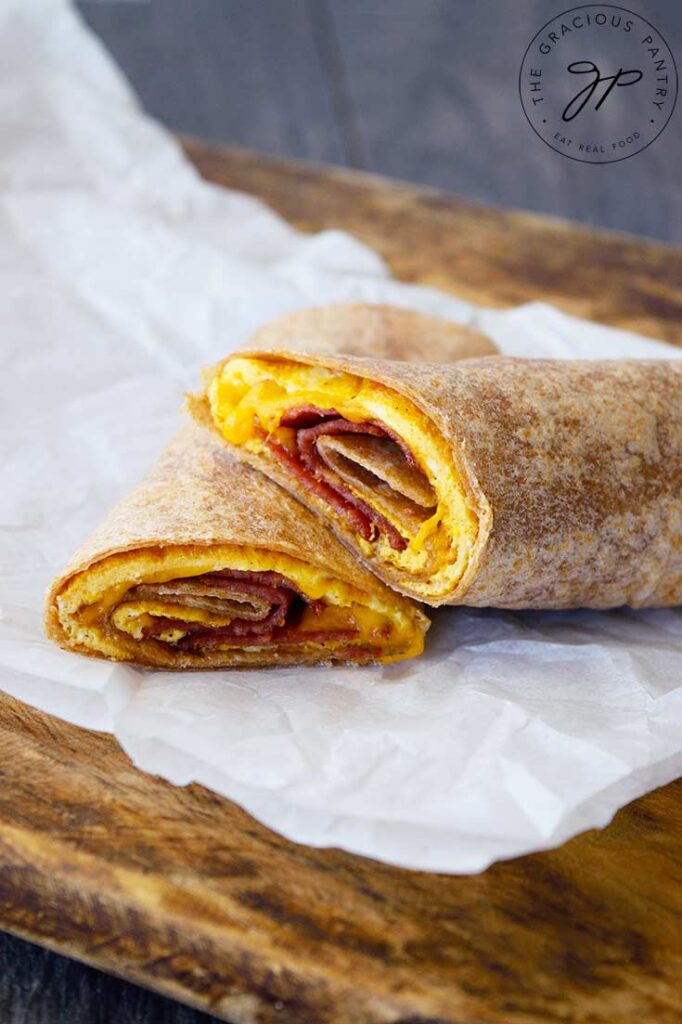 A cut Bacon And Egg Wrap sits stacked on a piece of parchment paper.