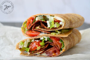A finished BLT Wrap laying stacked on a piece of parchment.