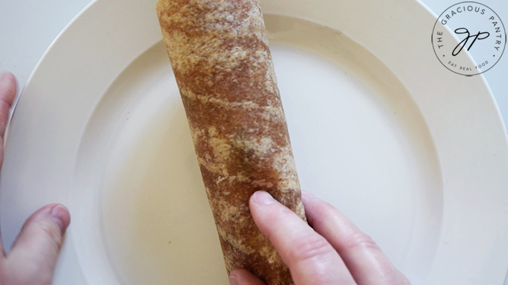 A rolled up BLT Wrap on a white plate.