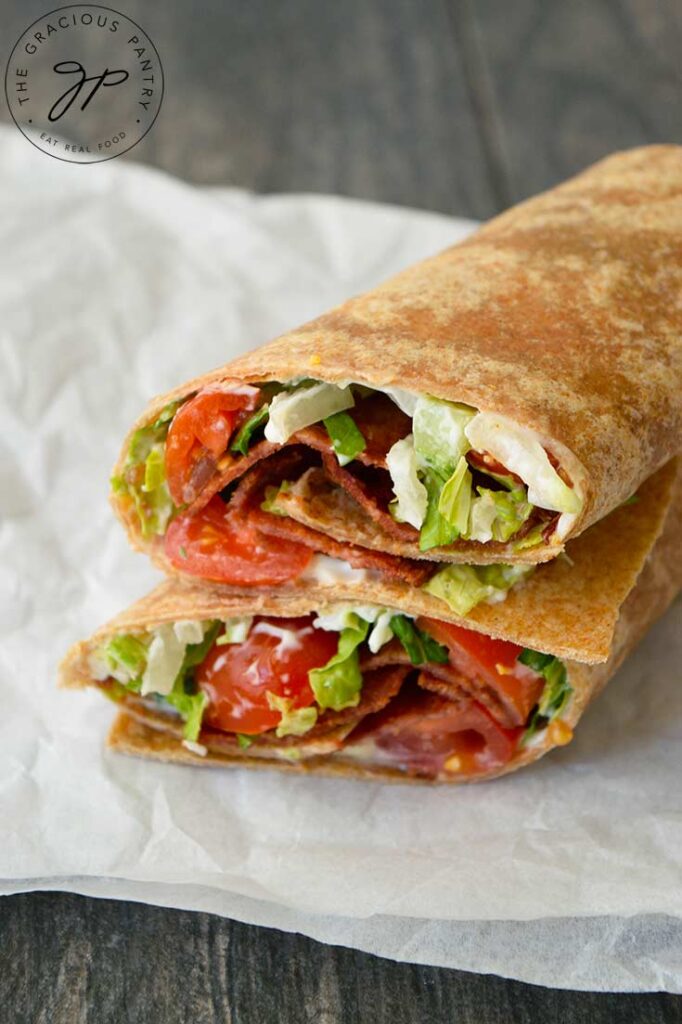 A front view of a cut BLT Wrap stacked and sitting on a piece of parchment.