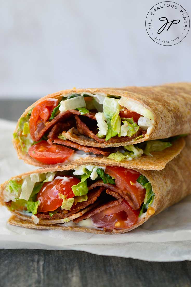 A view of the cut sides of a BLT wrap which have been stacked up on a piece of parchment paper.