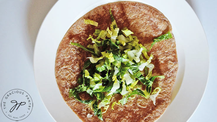 Lay down a layer of lettuce on the tortilla.
