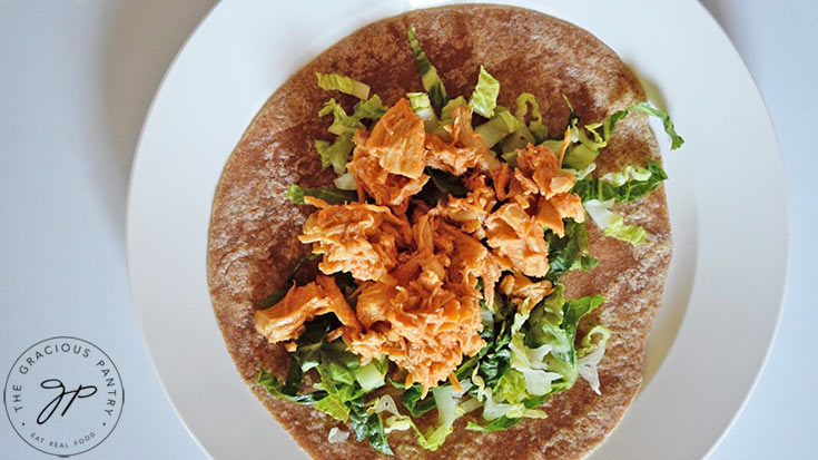 Buffalo chicken added to a tortilla with lettuce.