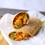 A buffalo chicken wrap cut and placed on a piece of parchment paper.