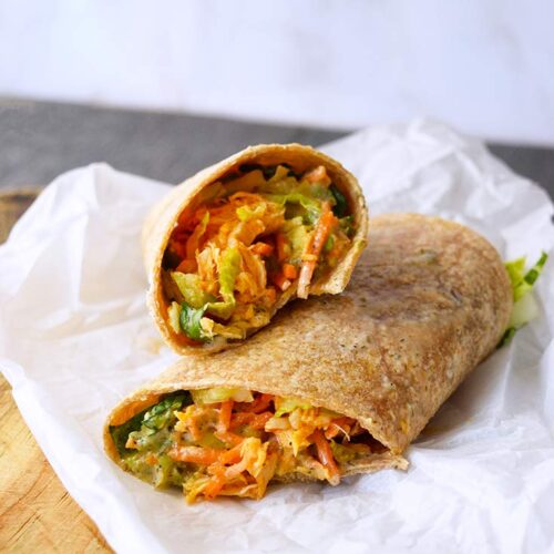 A buffalo chicken wrap cut and placed on a piece of parchment paper.