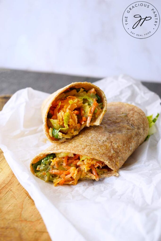 A buffalo chicken wrap cut and placed on a piece of parchment paper.