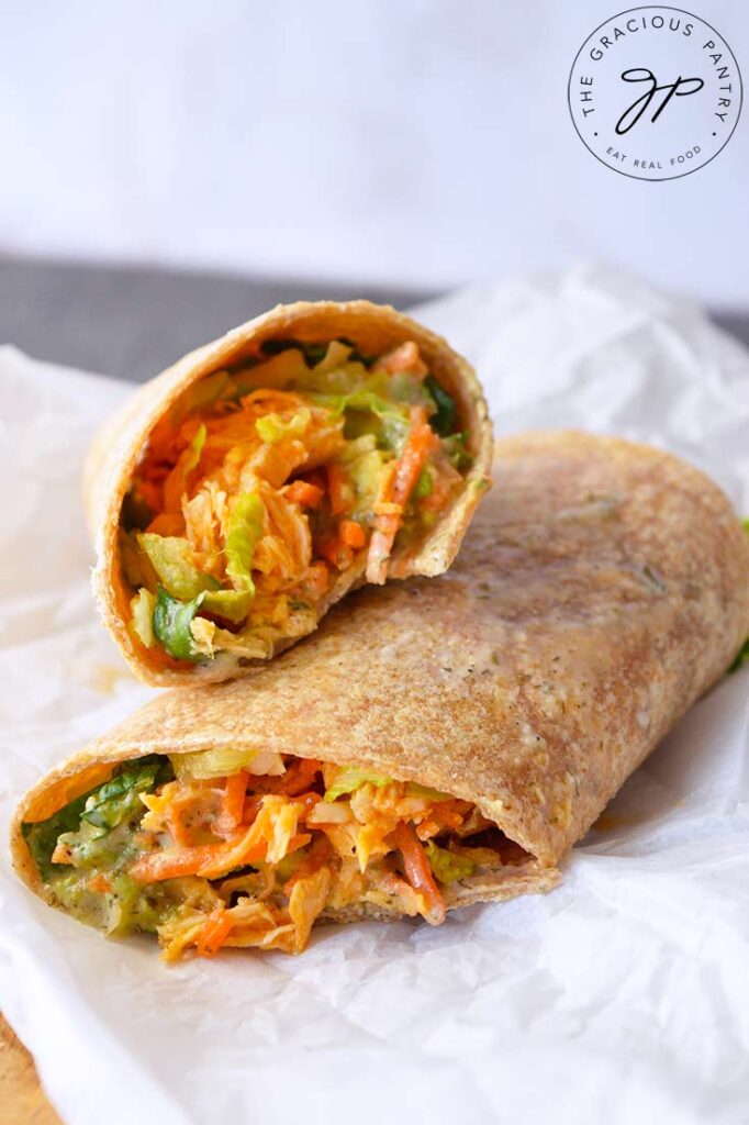 And up close view of the cut side of a Buffalo Chicken Wrap laying on a piece of parchment.