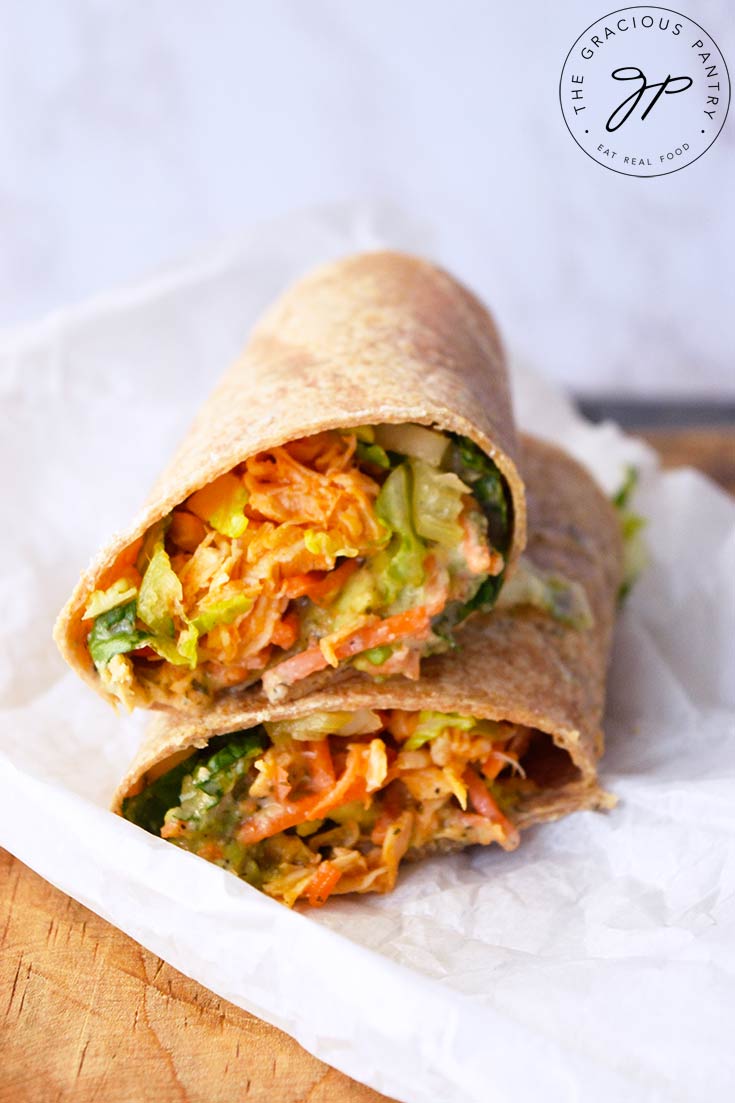 A Buffalo Chicken Wrap cut in half and stacked up on a piece of parchment paper.
