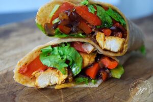 A cut Cajun Chicken Wrap sitting stacked on a cutting board.