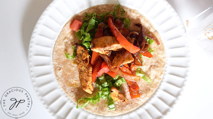 Chicken, peppers and onions laid over fresh lettuce and tomatoes on a whole grain tortilla.