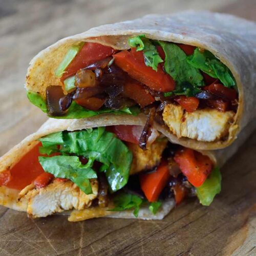 A front view of a cut Cajun Chicken Wrap sitting on a cutting board.