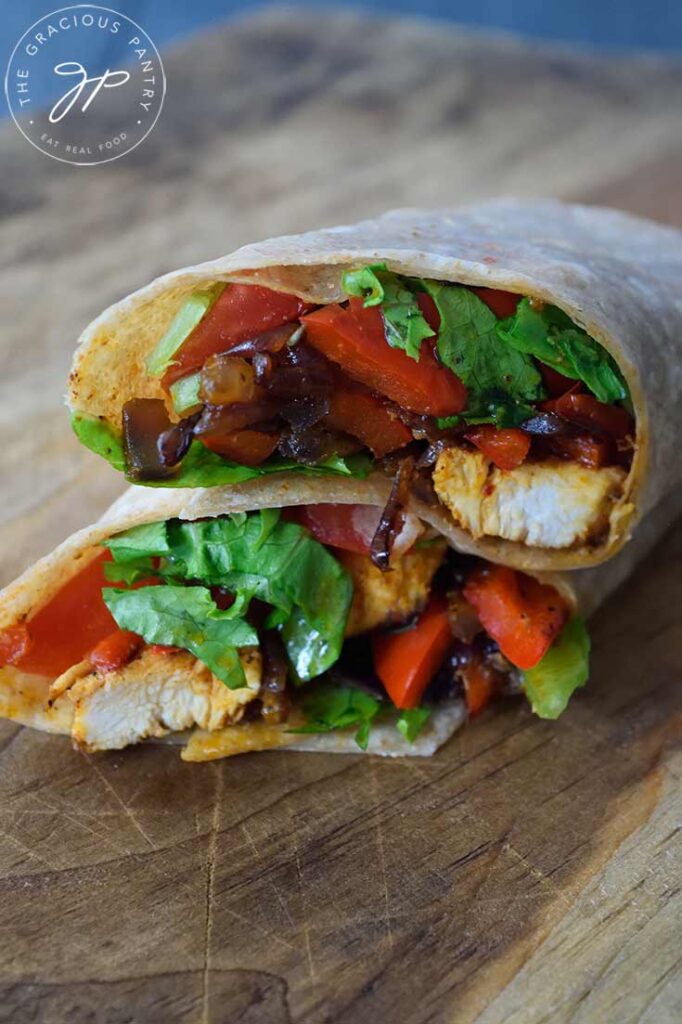 A front view of a cut Cajun Chicken Wrap sitting on a cutting board.