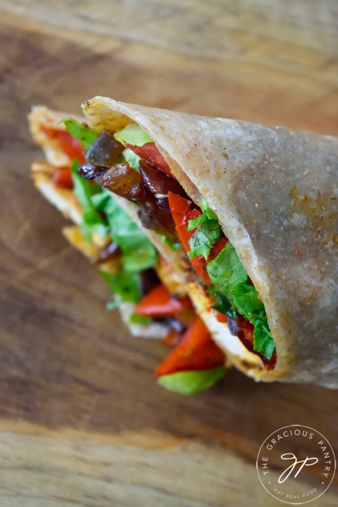 An overhead view looking down on a cut Cajun Chicken Wrap on a cutting board.